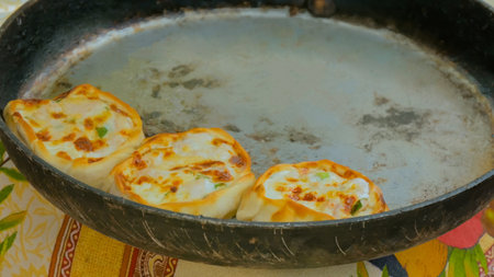 Process of cooking hot mini pies with chicken and cheese at street food festival. Outdoor cooking,...