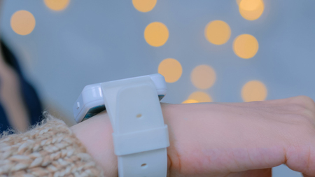 Woman using smart watch at home. Warm bokeh light background. Entertainment and technology concept. Close up shot of woman hand with smartwatchの写真素材