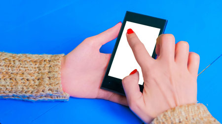 Woman using horizontal smartphone with white blank screen. Close up shot of woman hands with mobile. Technology, mock up and template conceptの写真素材