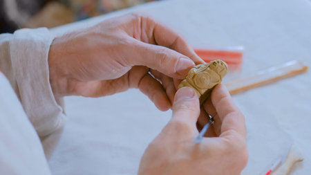 Professional male potter in russian ethnic shirt making clay figure for medieval popular strategy...