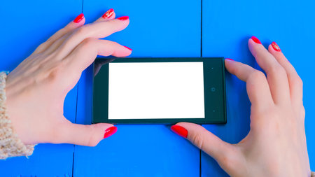 Woman looking at horizontal smartphone with white blank screen. Close up shot of woman hands with...