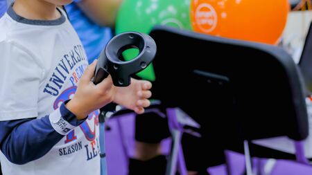 MOSCOW, RUSSIA - OCTOBER 12, 2018: Science Festival - teenager boy using virtual reality headset with controller sticks at futuristic exhibition. Gaming, VR and leisure time conceptのeditorial素材