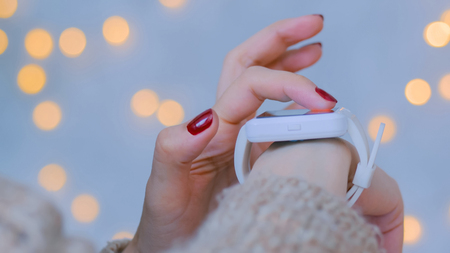 Woman using smart watch at home. Warm bokeh light background. Entertainment and technology concept. Close up shot of woman hand with smartwatchの写真素材