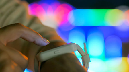 Young woman using wearable smartwatch computer device in the city - scrolling and touching. Evening...