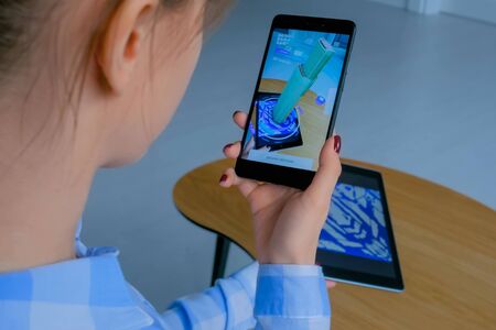 MOSCOW, RUSSIA - March 1, 2019. Woman using smartphone and tablet with augmented reality app and placing virtual model of skyscraper in room. Future, AR, architecture and technology conceptのeditorial素材