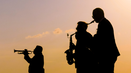 Unrecognizable brass band silhouette playing wind instruments at city street holiday, festival or carnival. Entertainment, music, urban culture and art conceptの写真素材