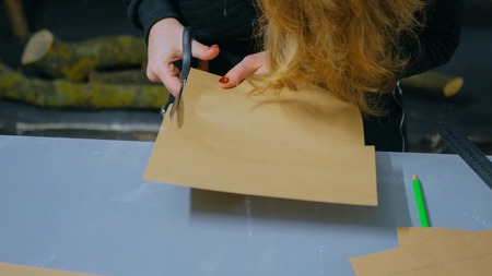 Close up shot - professional woman decorator, designer cutting kraft paper and making envelope at workshop, studio. Handmade and art conceptの写真素材