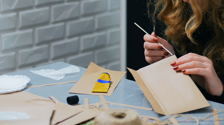 Professional woman decorator, designer working with kraft paper, applying glue and making envelope at workshop, studio - close up shot of woman hand. Design, handmade and art conceptの写真素材