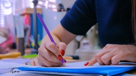 Close up shot - hands of professional tailor, designer drawing fashion sketch at atelier, studio....