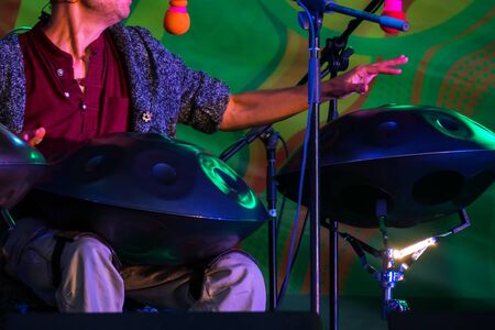 Man playing tank drum or hang on stage of ethnic open air concert. Relaxation, folk, meditative and traditional ethnic music conceptの写真素材
