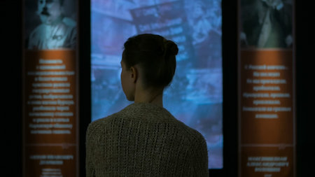 Young woman looking around in modern historical museum. Evening time, lowlight. Education and...