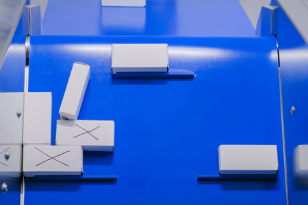 Top view - automatic production line with moving white small cardboard boxes on conveyor belt at...