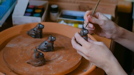 Professional woman potter, decorator painting ceramic souvenir penny whistle toy dog in pottery workshop, studio. Crafting, artwork and handmade conceptの写真素材
