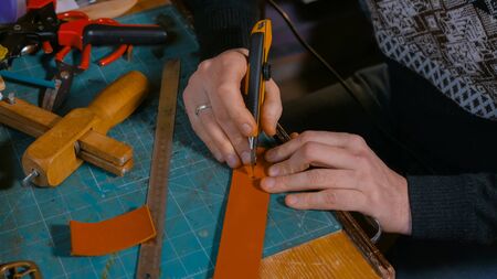 Professional male skinner, tanner working with genuine leather belt at workshop, studio. Handmade and leatherwork conceptの写真素材
