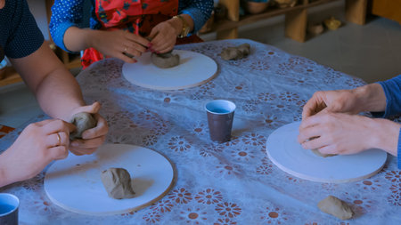 Pottery class and workshop: three people making clay mugs in pottery studio. Handmade, art and study...