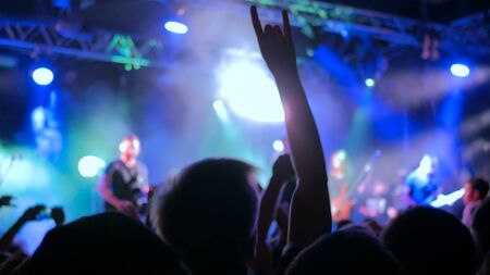 Silhouettes of people partying at rock concert in front of the stage. Entertainment and leisure conceptの写真素材