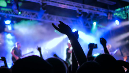 Silhouettes of people partying at rock concert in front of the stage. Entertainment and leisure...