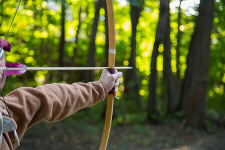 Medieval male archer shooting targets with wooden bow at historical festival - close up shot. Archery and medieval culture conceptの写真素材