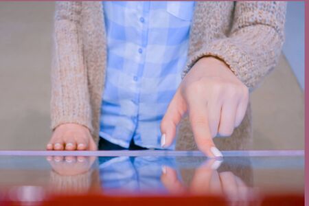 Education and technology concept - woman using interactive touchscreen display of red electronic kiosk at technology exhibition or museumの写真素材