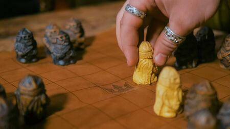 Game preparation - close up shot of man hand placing figures for medieval popular strategy board game - tafl. Folk, competition and traditional conceptの写真素材