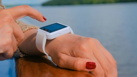 Woman using wearable smartwatch computer device on deck of cruise ship at sunset. Sunset light, golden hour. Technology and journey conceptの写真素材