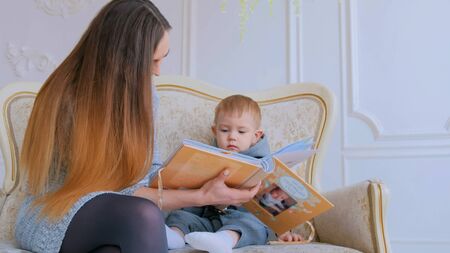 Young mother and her baby son looking photobook togerher at home. Family, childhood and leisure conceptの写真素材