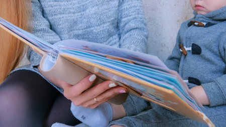 Young mother and her baby son looking photobook togerher at home - close up shot. Family, childhood and leisure conceptの写真素材