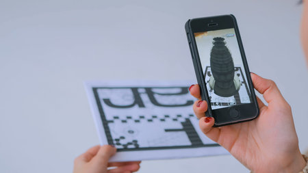 MOSCOW, RUSSIA - AUGUST 29, 2018. Woman using smartphone with augmented reality app and placing...