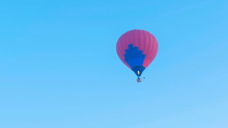 Hot air balloon takes off against blue skyの写真素材