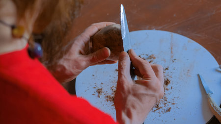 Professional male potter shaping and scraping dry clay cup with special tool in pottery workshop,...