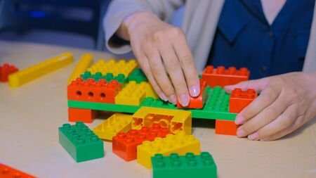 Close up shot of woman hands playing with colorful plastic blocks constructorの写真素材