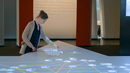 Woman using interactive touchscreen display at modern history museum - scrolling and touching....