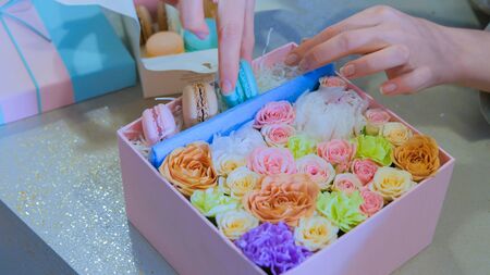 Professional woman floral artist, florist making gift box with flowers at workshop, flower shop. Floristry, handmade and small business conceptの写真素材
