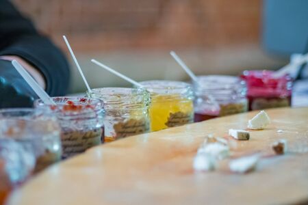 Delicious colorful jam, jelly or confiture in little glass jars and cheese slices for tasting on counter of shop, market, cafe. Dessert, confectionery, gastronomy and food conceptの写真素材