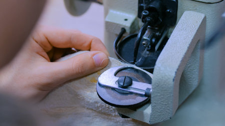 Professional male skinner, furrier using special sewing machine for stitching fur skin at atelier,...