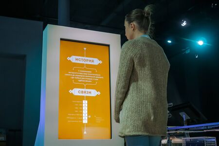 MOSCOW, RUSSIA - JUNE 05, 2019: Smart Expo. Woman looking at interactive display kiosk and reading presentation about history of russian internet at exhibition or museum with futuristic interiorのeditorial素材