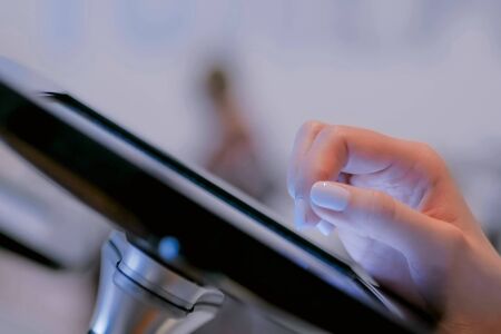 Woman hand using touchscreen display of interactive floor standing black tablet kiosk at exhibition or museum - close up view. Futuristic, education, entertainment, learning, technology conceptの写真素材