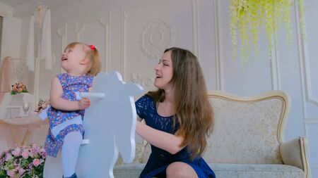 Little girl playing on white wooden rocking horse. Family, childhood, game and leisure conceptの写真素材
