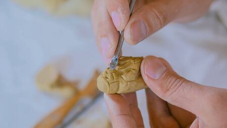 Professional male potter making clay figure for medieval popular strategy board game - tafl. Handwork, crafting and traditional arts conceptの写真素材