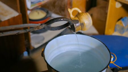 Professional male potter quenching hot ceramic mug after burning in cold water at pottery, workshop. Handmade, craftsmanship and authentic conceptの写真素材