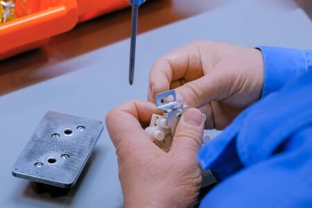 Blind man assembler, electrician hands assembling electric socket at fabric. Repair, production, handmade manufacturing process, electricity and disabled people conceptの写真素材