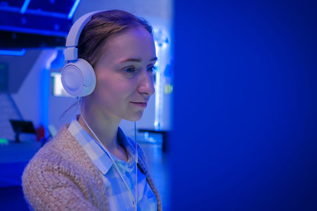 Woman looking at exposition, using white headphones and listening audio guide at modern futuristic exhibition or museum. Education, sci-fi, interactive, technology, future and entertainment conceptの写真素材