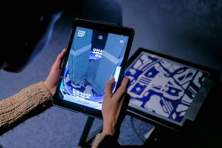 MOSCOW, RUSSIA - March 1, 2019. Woman using digital tablet device with augmented reality app and spinning virtual model of modern building in room. Future, AR, architecture and technology conceptのeditorial素材