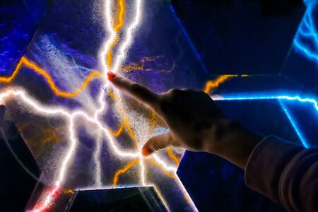 Interactive touchscreen exposition in science museum. Woman touching plasma panel display. Electricity, education, science, futuristic and physics conceptの写真素材