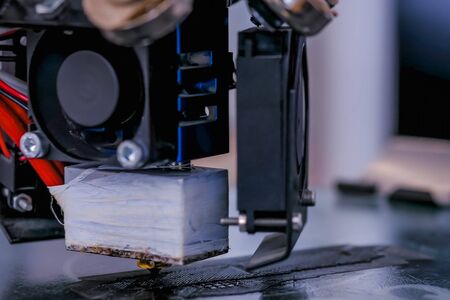 Print head of 3D printer machine printing plastic model at modern scifi technology exhibition - close up view. 3D printing, additive technologies, 4.0 industrial revolution and futuristic conceptの写真素材