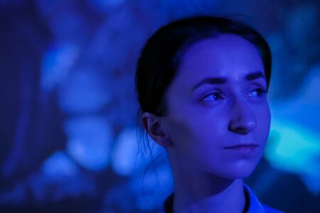 Portrait of woman face looking around at modern immersive exhibition with low light illumination and colorful video art installation. Education, digital art and entertainment conceptの写真素材