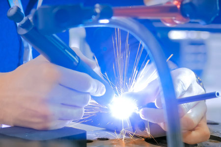 Professional male welder trying gas tungsten arc welding GTAW or tungsten inert gas TIG technology...