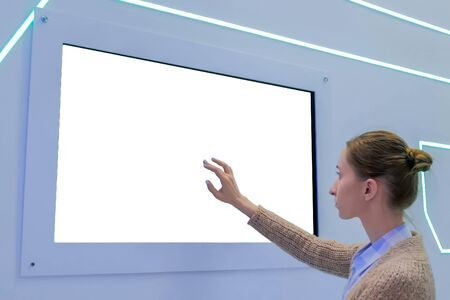 White screen, mock up, future, copyspace, template, isolated, technology concept. Woman touching blank digital interactive white display wall at exhibition or museum with futuristic scifi interiorの写真素材