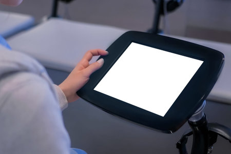 Woman looking at floor standing tablet kiosk with blank white display at exhibition or museum -...