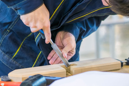 Professional man carpenter using chisel to carve wood on rough workbench at workshop. Design,...